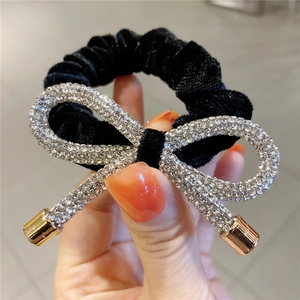 Elegant black velvet scrunchie with a large rhinestone bow decoration and gold metal tips