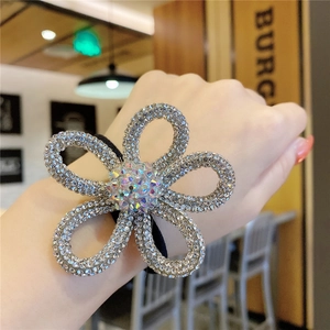 Close-up of sparkling floral hair tie with rhinestones worn on a woman's wrist
