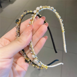Gros plan de serre-têtes élégants avec perles et strass sur tissu noir et crème