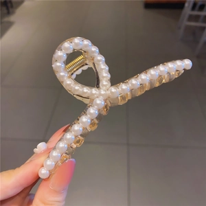 Détail d'une élégante pince à cheveux dorée ornée de perles blanches pour femmes