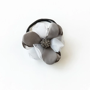 Détail d'un chouchou fleur en organza multicouche avec centre en strass et bande élastique