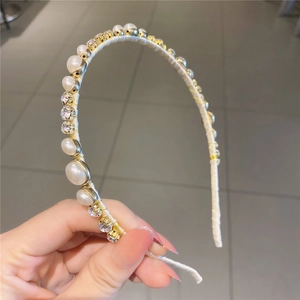 Détail d'un serre-tête élégant avec perles blanches et cristaux sur monture dorée