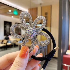 Detail of flower hair tie featuring silver rhinestones and central iridescent crystal