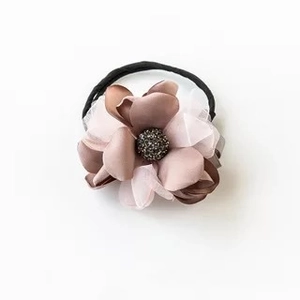 Détail d'un chouchou fleur aux tons Morandi avec pétales en satin et perles centrales