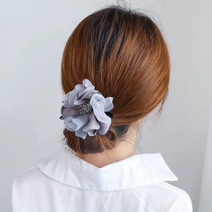 Barrette fleur en mousseline grise avec strass portée sur un chignon élégant