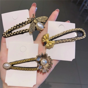 Detail of bee, bow, and daisy hair clips set with pearls and rhinestones on cards