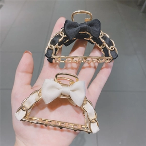 Elegant metal bow hair claw clips in black and cream with gold chain woven detail