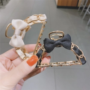 Detail of elegant black and cream bow hair clips with golden woven metal chains