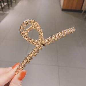 Détail d'une pince à cheveux en métal doré avec un design de chaîne tressée élégante