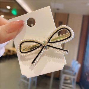 Dettaglio di un fermaglio per capelli a fiocco dorato con perle bianche e strass