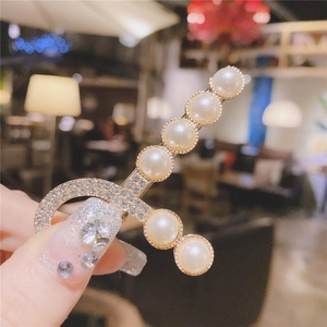 Détail d'une élégante pince à cheveux dorée avec perles blanches et strass brillants