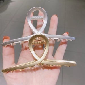 Close-up of matte gold and silver hollowed-out metal claw clips in a minimalist design