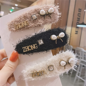 Detail of plush hair clips with pearl bows, rhinestones, and gold metal lettering set