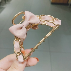 Detail of pink ribbon and golden metal chain woven design on a bow claw hair clip