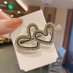 Dettaglio del fermaglio per capelli dorato a forma di cuore con strass e smalto nero