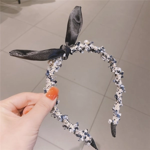Detail of tweed headband featuring a black satin bow and white pearl accents