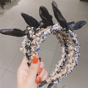 Close-up of elegant tweed hairbands featuring faux pearls and black satin bows set