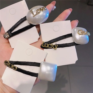 Dettaglio di fermagli per capelli in perle francesi con scritte Love e Lucky dorate