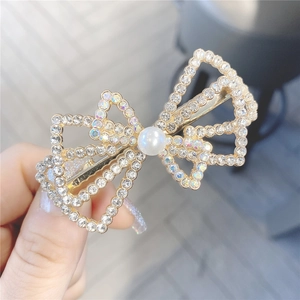 Barrette à cheveux nœud évidé avec strass brillants et perle blanche au centre