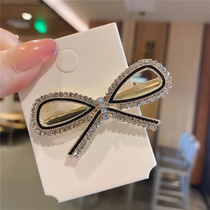 Dettaglio di un fermaglio a fiocco con strass scintillanti e bordi neri eleganti