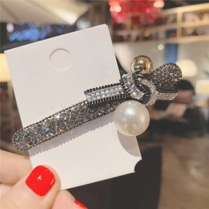 Détail d'une barrette nœud de luxe en strass avec grosse perle blanche et perle dorée