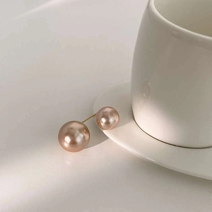 Gros plan de perles rose champagne sur épingle dorée près d'une tasse en porcelaine