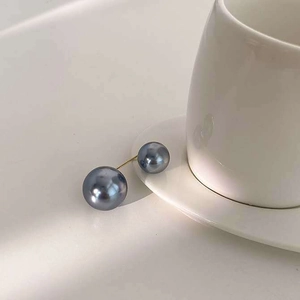 Détail de perles grises avec tige dorée posées sur une tasse en porcelaine minimaliste