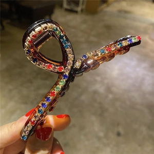 Dettaglio con strass colorati su una grande pinza per capelli marrone caffè traslucido