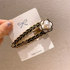 Detailed side view of woven hair clip with white camellia flower and pearl accent