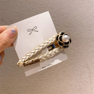 Detail of woven leather hair clip with black and white camellia flower and pearl