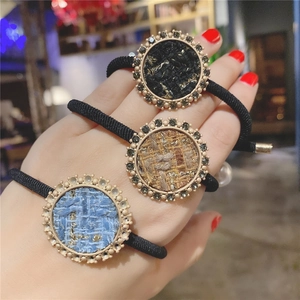 Close-up of elegant tweed hair scrunchies with rhinestone circle charms and elastic bands