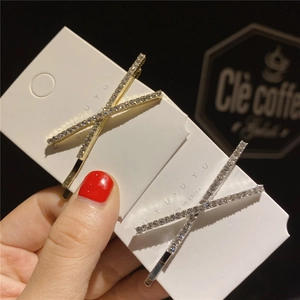 Détail de deux barrettes en forme de X dorées et argentées ornées de strass brillants