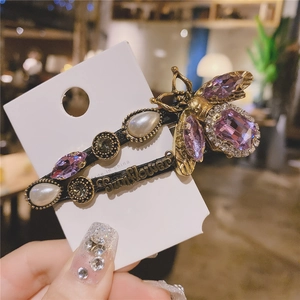 Detail of vintage gold bee hair clip with purple crystal and teardrop pearl on card