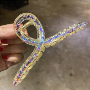Dettaglio di una grande pinza per capelli trasparente con strass colorati in mano