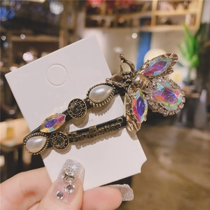 Detailed macro shot of vintage gold bee hair clip with rainbow crystals and pearls