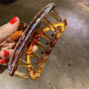 Detail of amber resin hair claw with iridescent rhinestones for half-up hairstyles