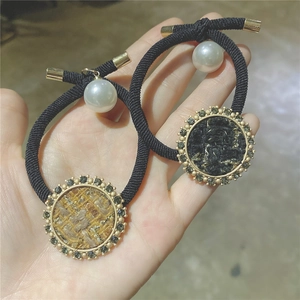 Elegant tweed fabric hair ties with rhinestone trim and faux pearl accents in a hand shot