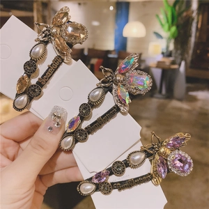 Detail of vintage gold bee hair clips with crystals, pearls and engraved metal