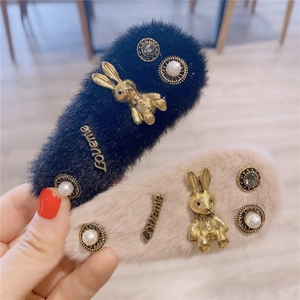 Gros plan de barrettes en peluche avec breloques lapin et Loveme en noir et beige