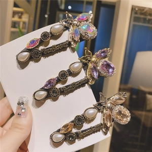 Detail view of three retro bee hair clips with pearls and colorful rhinestones