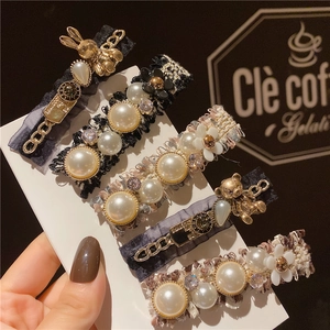 Détail du lot de 5 barrettes à fleurs avec perles et strass sur support blanc