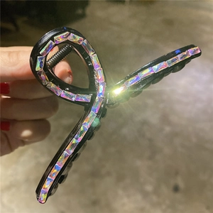 Dettaglio di una grande pinza per capelli nera con strass iridescenti rettangolari in mano