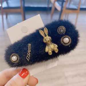 Détail d'une pince à cheveux en peluche noire avec lapin doré et strass brillants