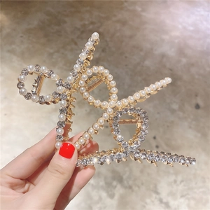 Détail d'une grande pince à cheveux dorée ornée de perles et de strass scintillants