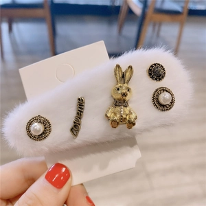Détail d'une barrette en peluche blanche avec lapin doré, perles et décor Loveme
