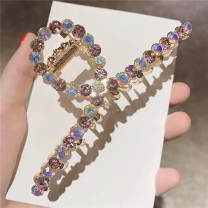 Détail de la grande pince à cheveux dorée croisée avec strass roses et ressort robuste