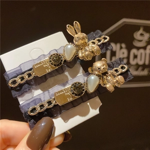 Détail de pince à cheveux avec ours doré, dentelle, chaîne et perle décorative