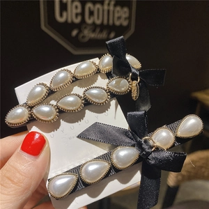 Elegant bow hair clips featuring white pearl clusters and black satin on gold metal