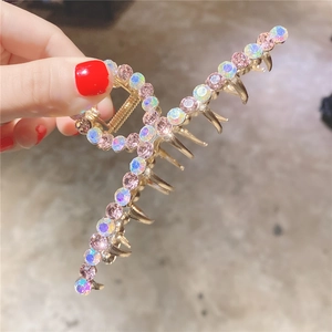 Détail d'une grande pince à cheveux dorée avec cristaux roses et AB à la main