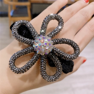 Detailed view of the sparkling floral hair tie with rhinestones on a black velvet base